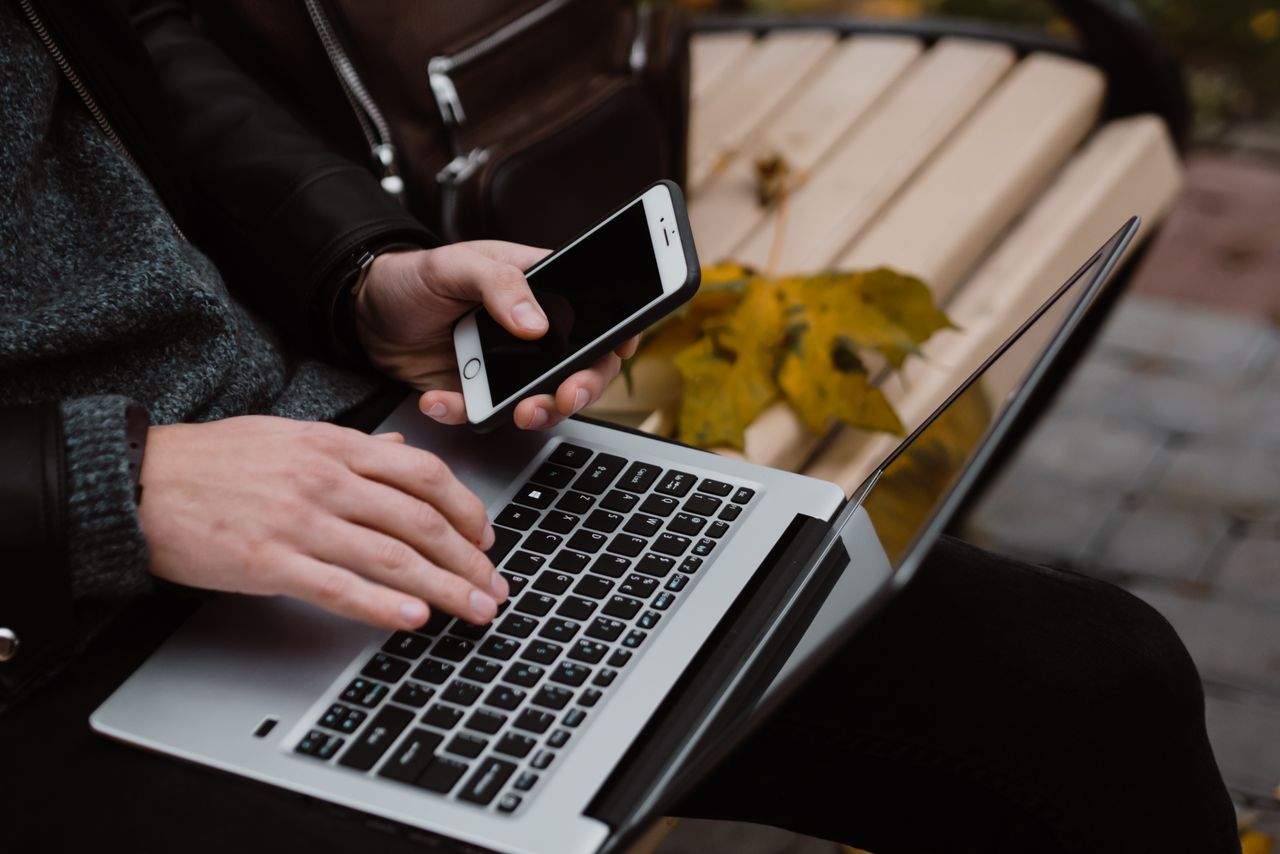 why-choose-us Person working remotely using a laptop and smartphone outdoors, embodying digital nomad lifestyle.