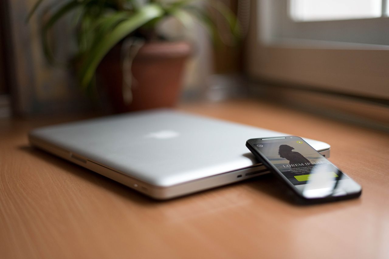 services-03 Close-up of a silver laptop and smartphone on a wooden desk, capturing modern work essentials.